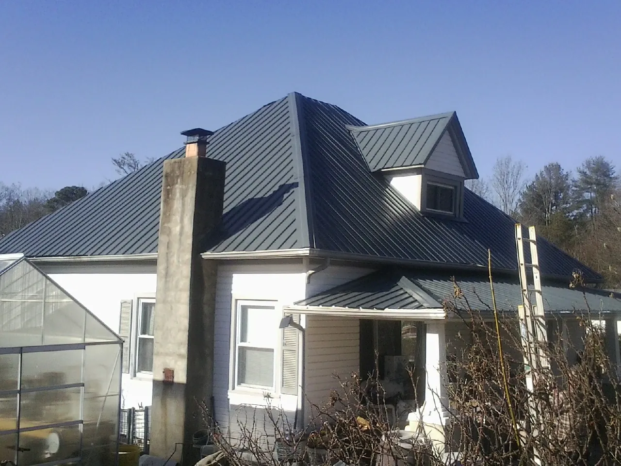 Dark blue standing seam metal roof on a white farmhouse with dormer — Slate & Tile Roof Repair by Roofing Brothers in Harwood Heights
