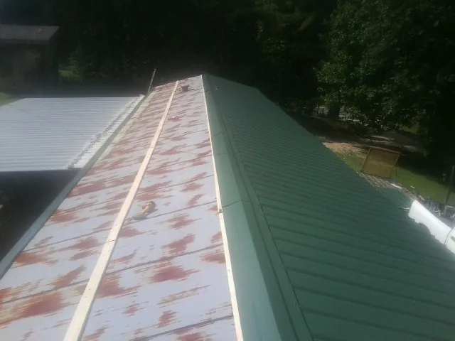 Old rusted panels beside newly installed green metal roofing — Wind Damage Roof Repair by Roofing Brothers in Harwood Heights