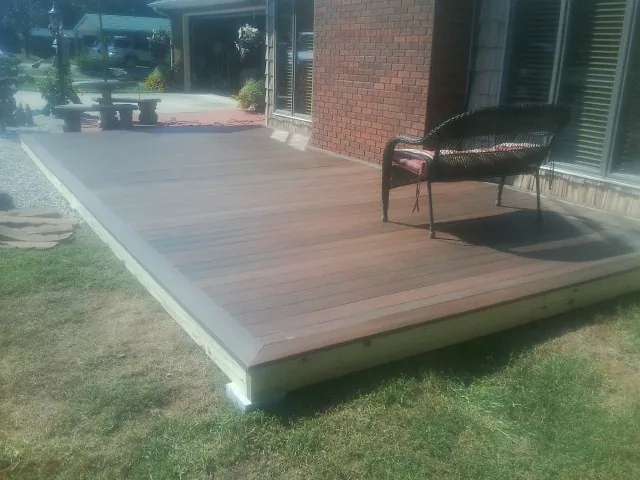 New wood deck and wicker chair beside a brick house in Harwood Heights