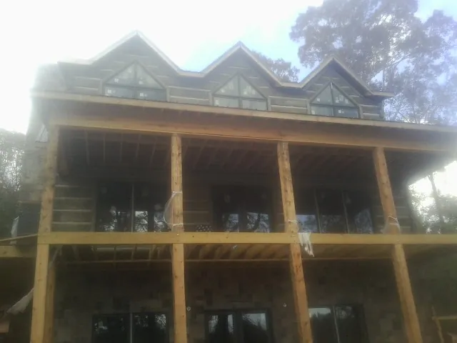 Dormers and porch framing on a large log home under construction — Roof Coating work by our crew in Harwood Heights