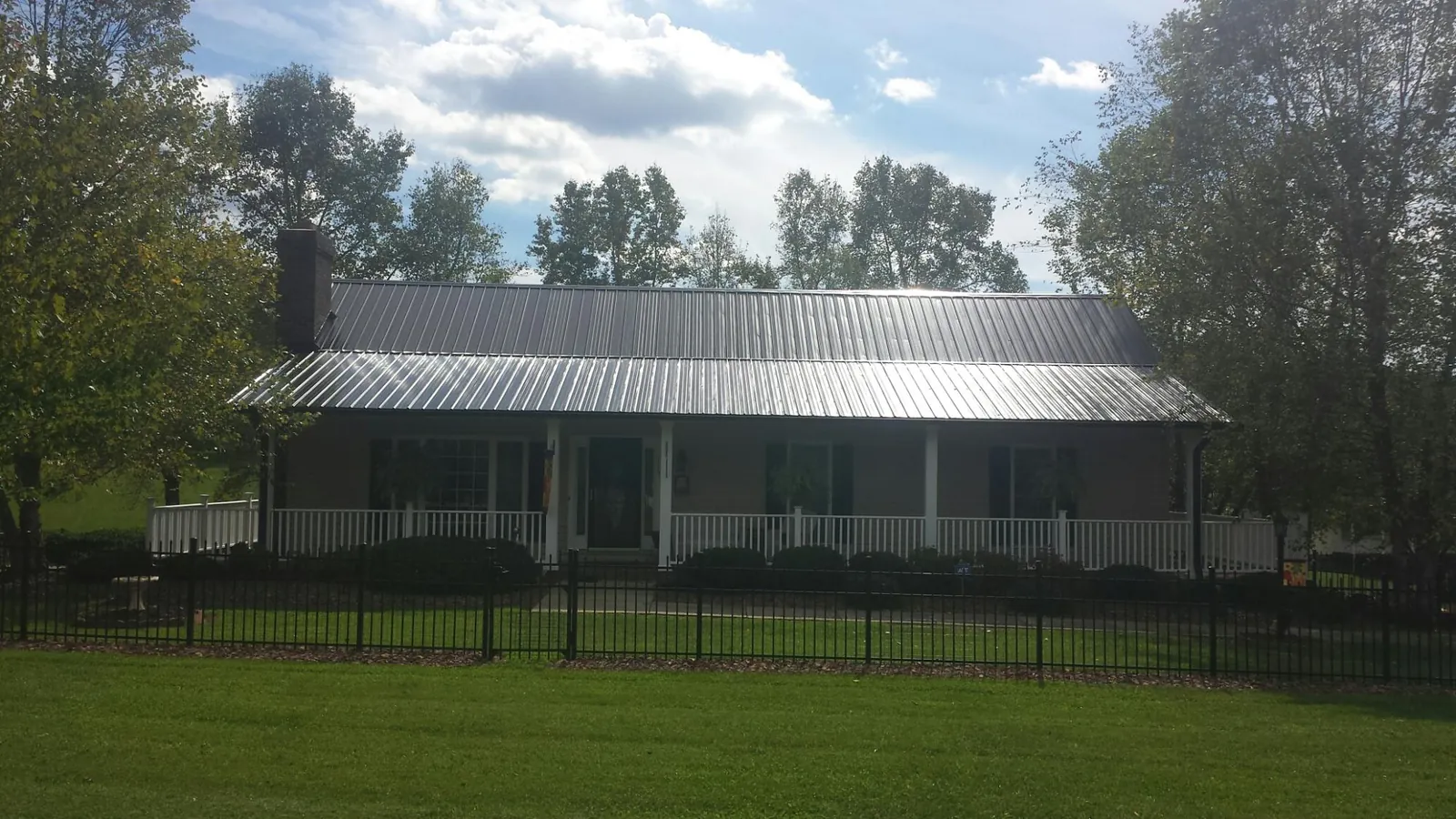 Gray metal roof on a brick ranch with a full width front porch — Gutter Guard Installation work by our crew in Harwood Heights