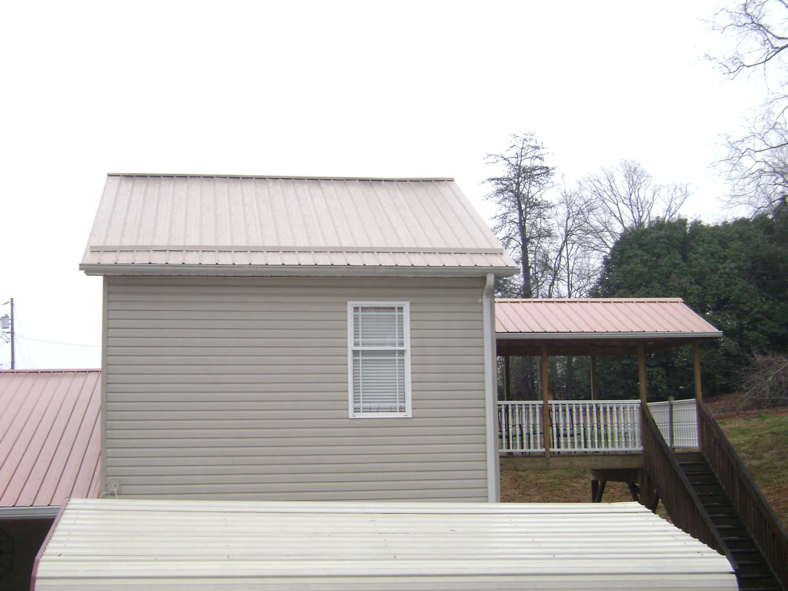 Tan metal roofs on a two story addition and attached porch, from a Roof Replacement job in Harwood Heights