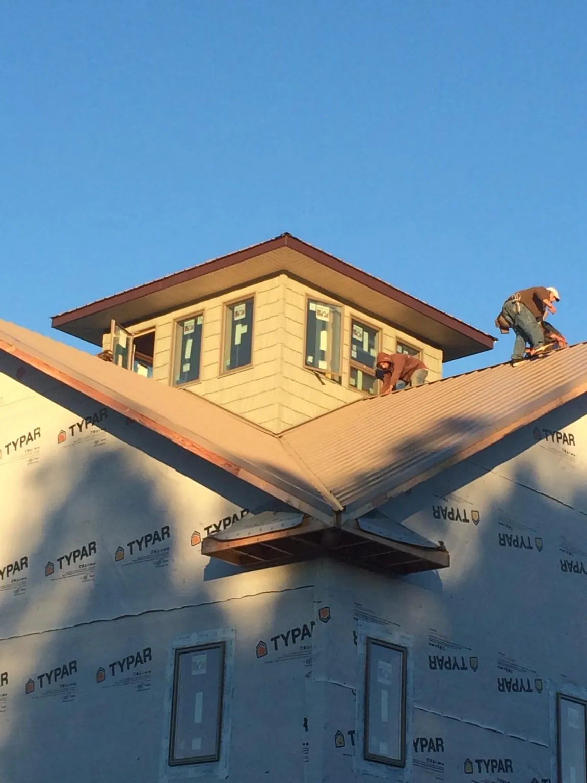 Roofers working around a rooftop cupola on a new metal roof at sunset — Roof Waterproofing in Harwood Heights by Roofing Brothers